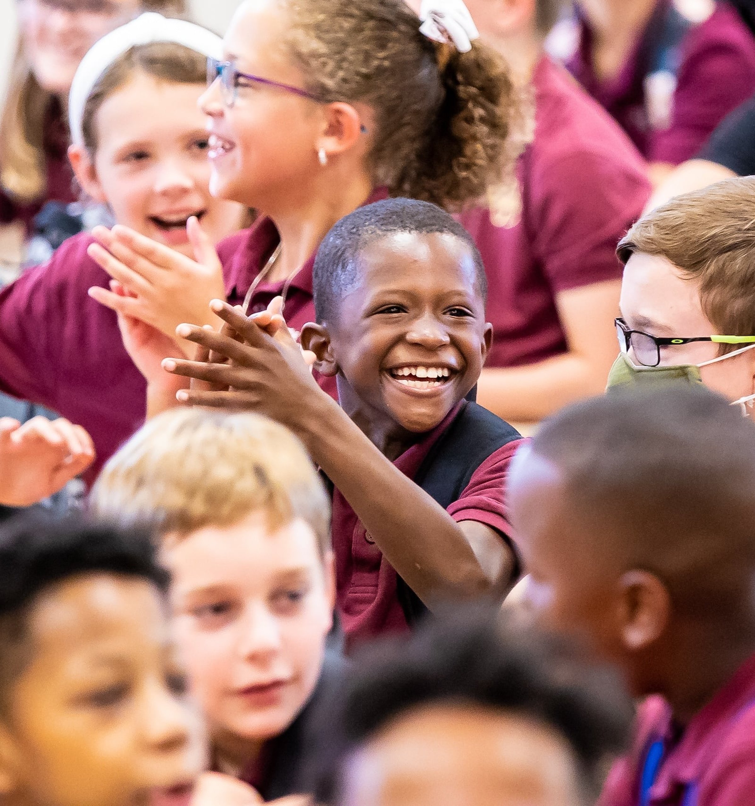 Walker students clapping and smiling while sitting on the floor 