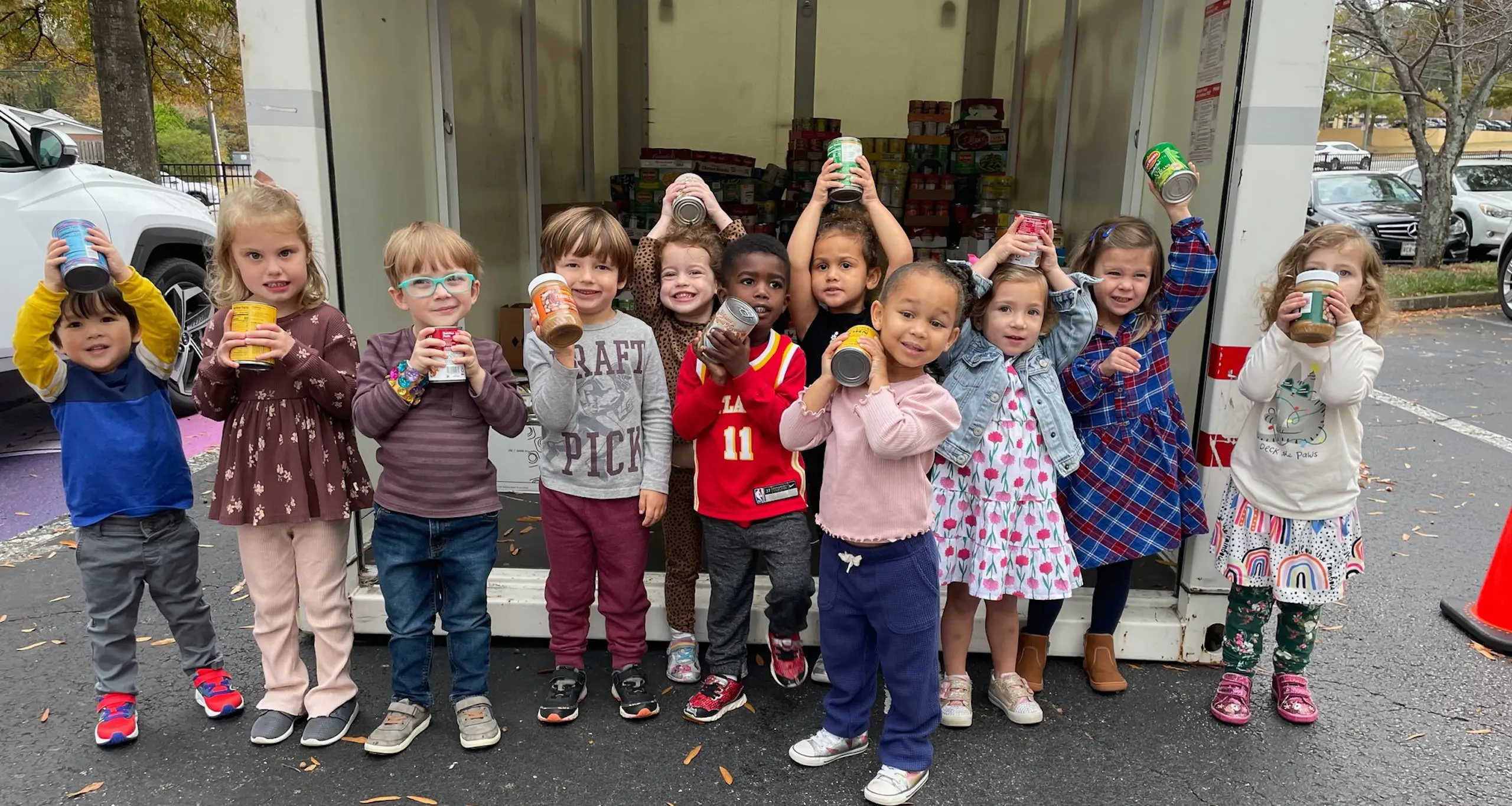 Young Walker students holding up canned food