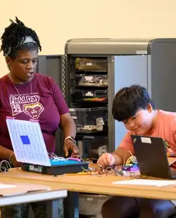 Teacher working with student in computer science lesson