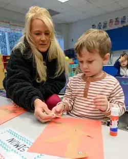 Teacher helping student with craft paper