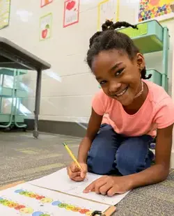 Student kneeling on floor, drawing