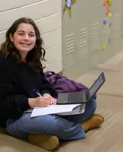 Student sitting on the floor, smiling