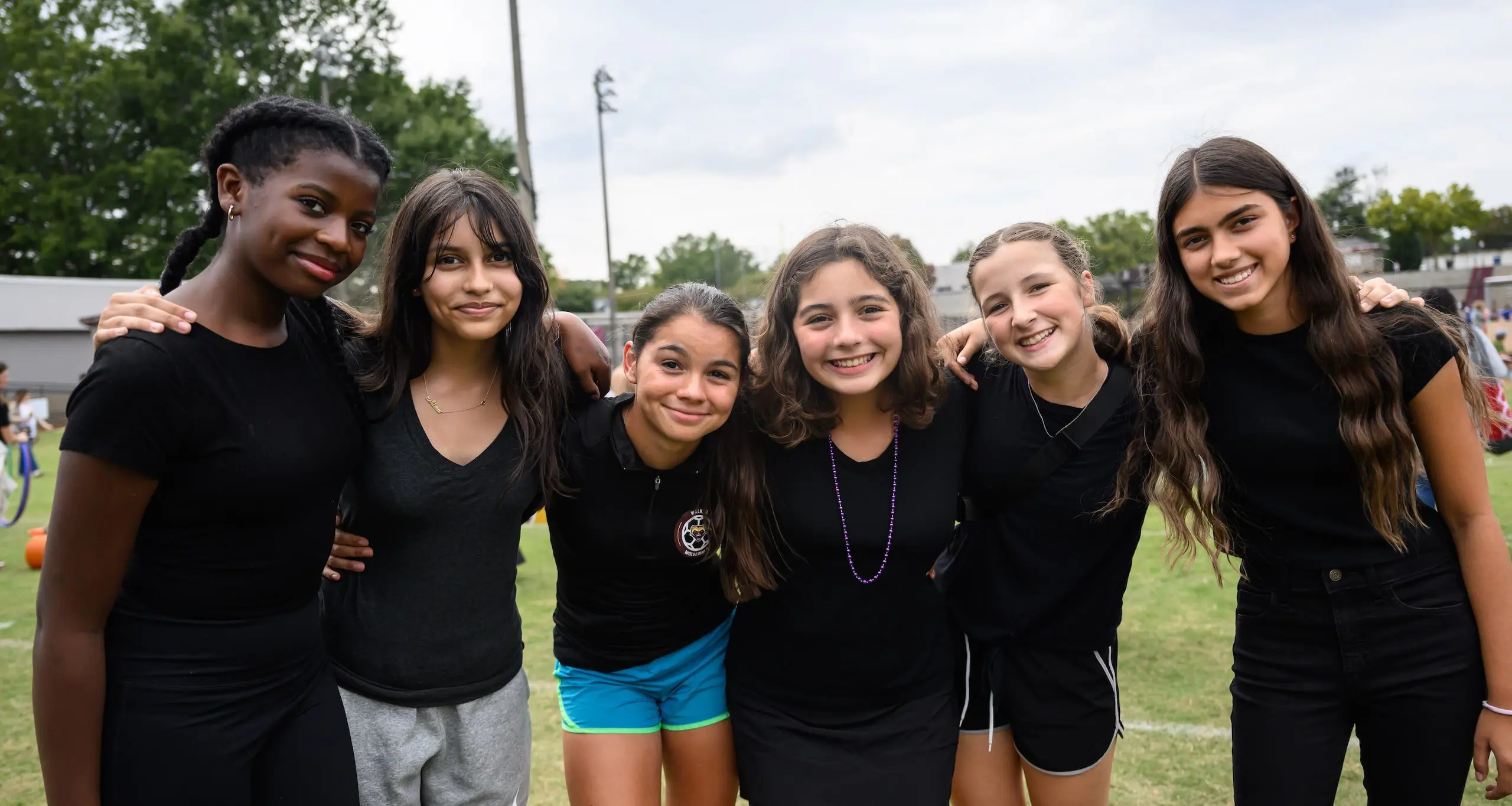 Group of female Walker students wearing sports attire in a semi circle smiling at camera