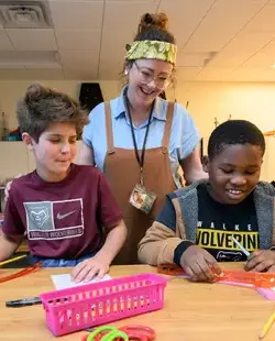 Teacher smiling down at two students