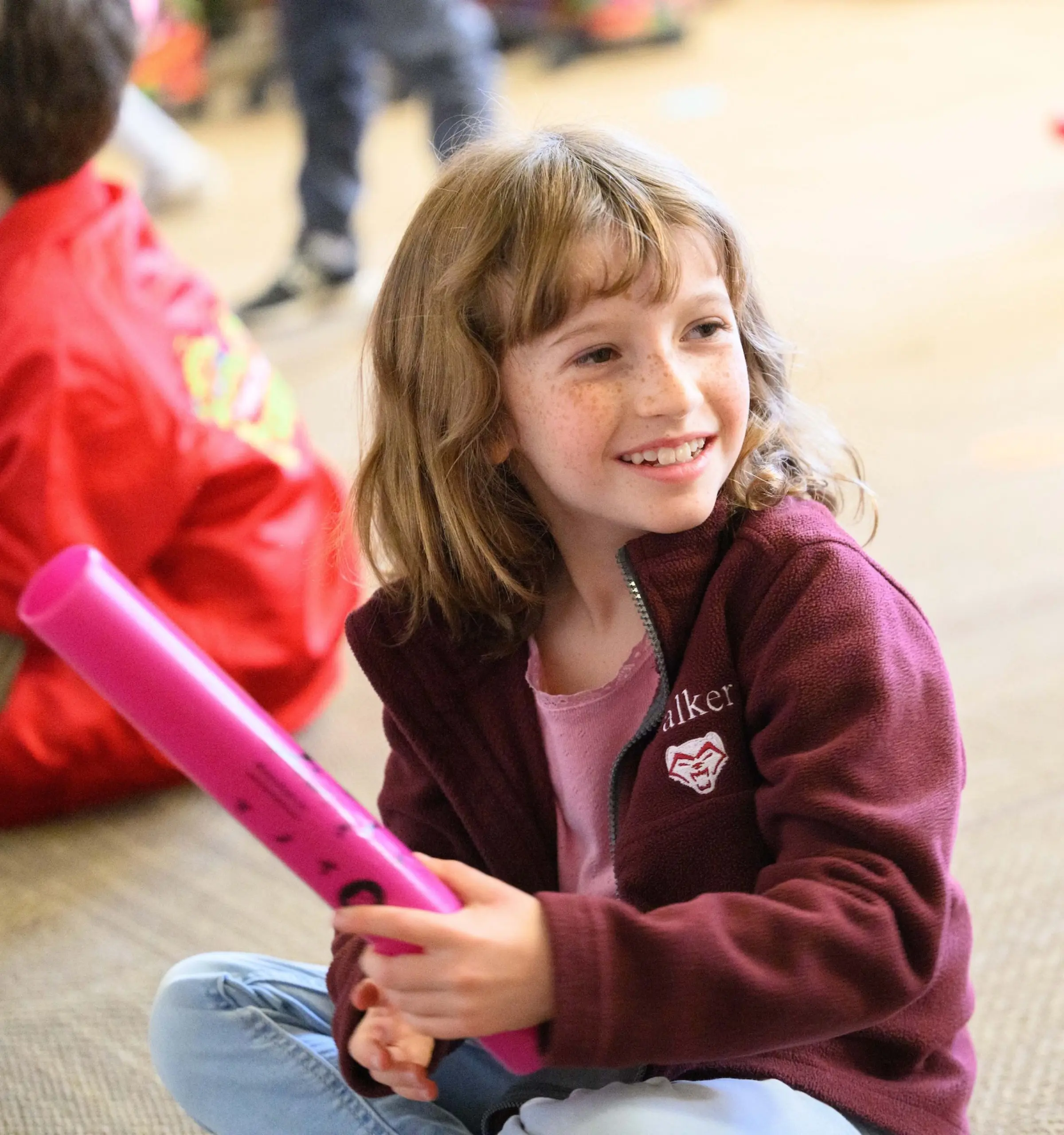 Walker student sitting on carpet holding pink equipment