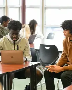 Students talking next to a laptop